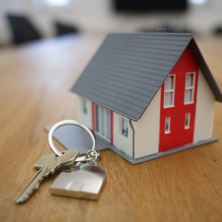 Hausmodell auf Tisch mit Schlüsseln – Symbol für Immobilienschenkung und Erbschaft